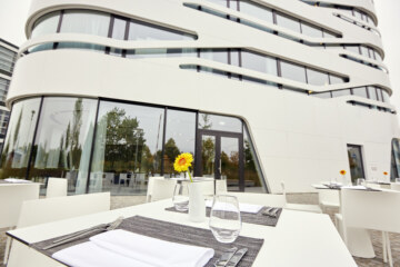 Ein gedeckter Tisch vor dem beeindruckenden Gebäude des Designhotels bei München.