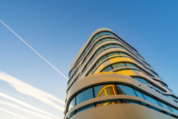 Das geschwungene Design des Hotels in Planegg vor blauem Himmel.
