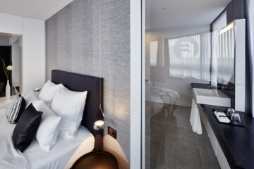 Blick in den Schlaf- und Badbereich in einer der Doppelzimmer der modernen Unterkunft bei München.