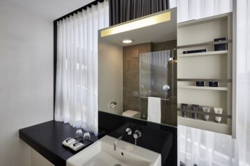 Bright bathroom with various cosmetic products and mirrors in the modern hotel room in Munich.