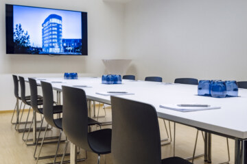 Konferenzraum "Ellipse 2" in der Tagungslocation bei München mit länglichem Tisch und Bildschirm.